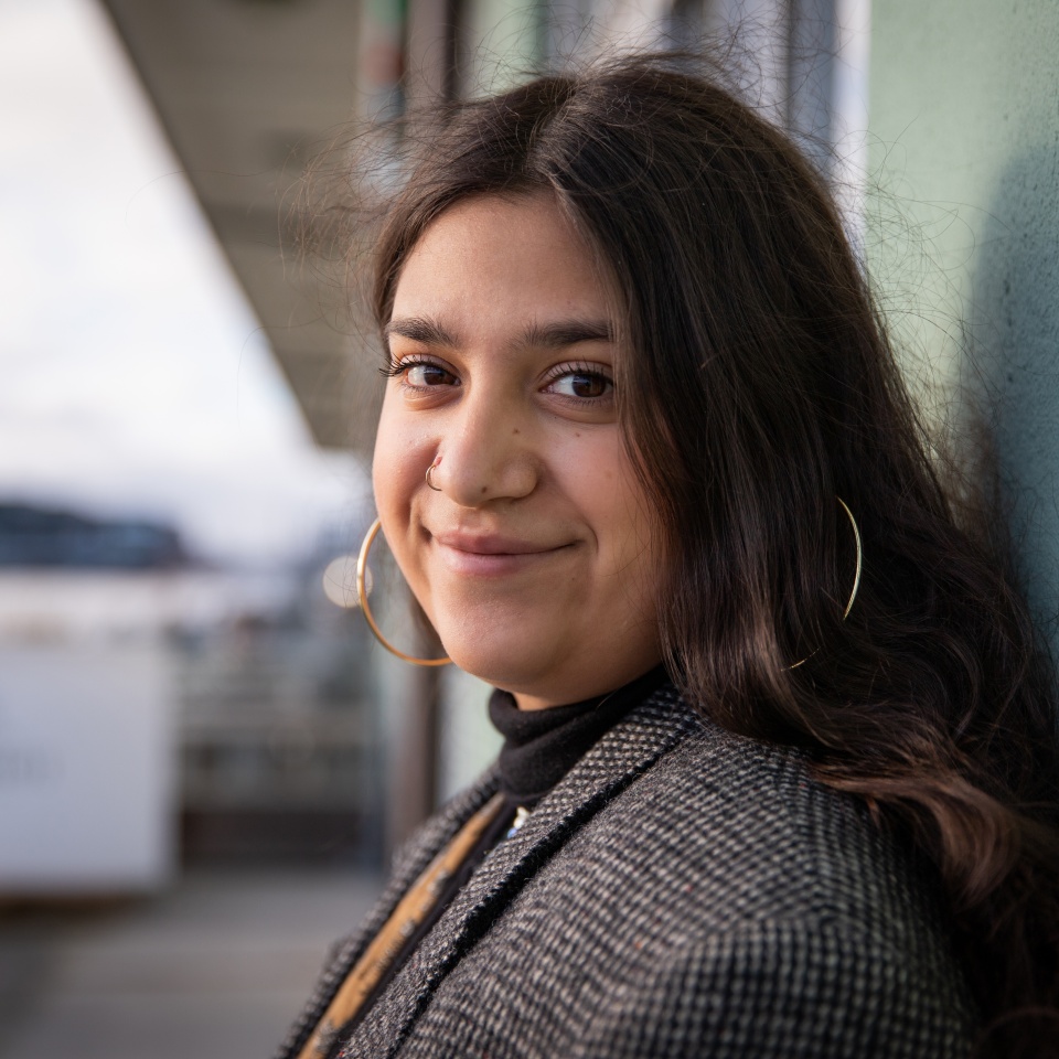 Portrait of a smiling young girl. Happy and calm teenage female is leaning with her back against a wall. Beautiful North African girl. Happy youth concept