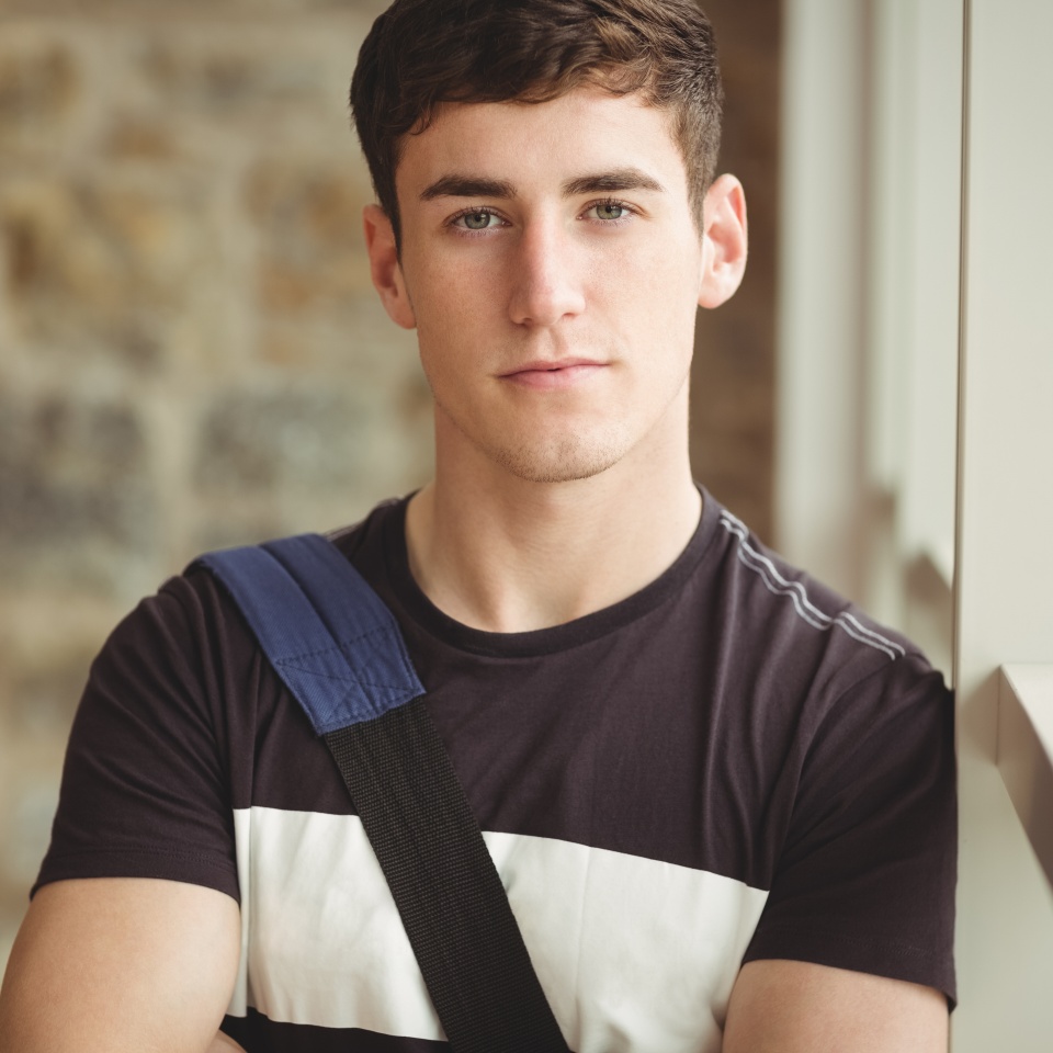 Portrait of confident male leaning on window glass in college