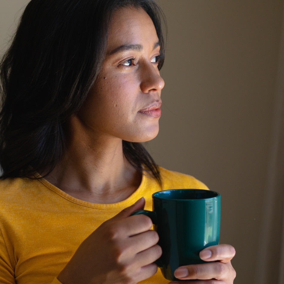Young african american woman thinking while holding coffee mug at home. people and emotions concept, unaltered.
