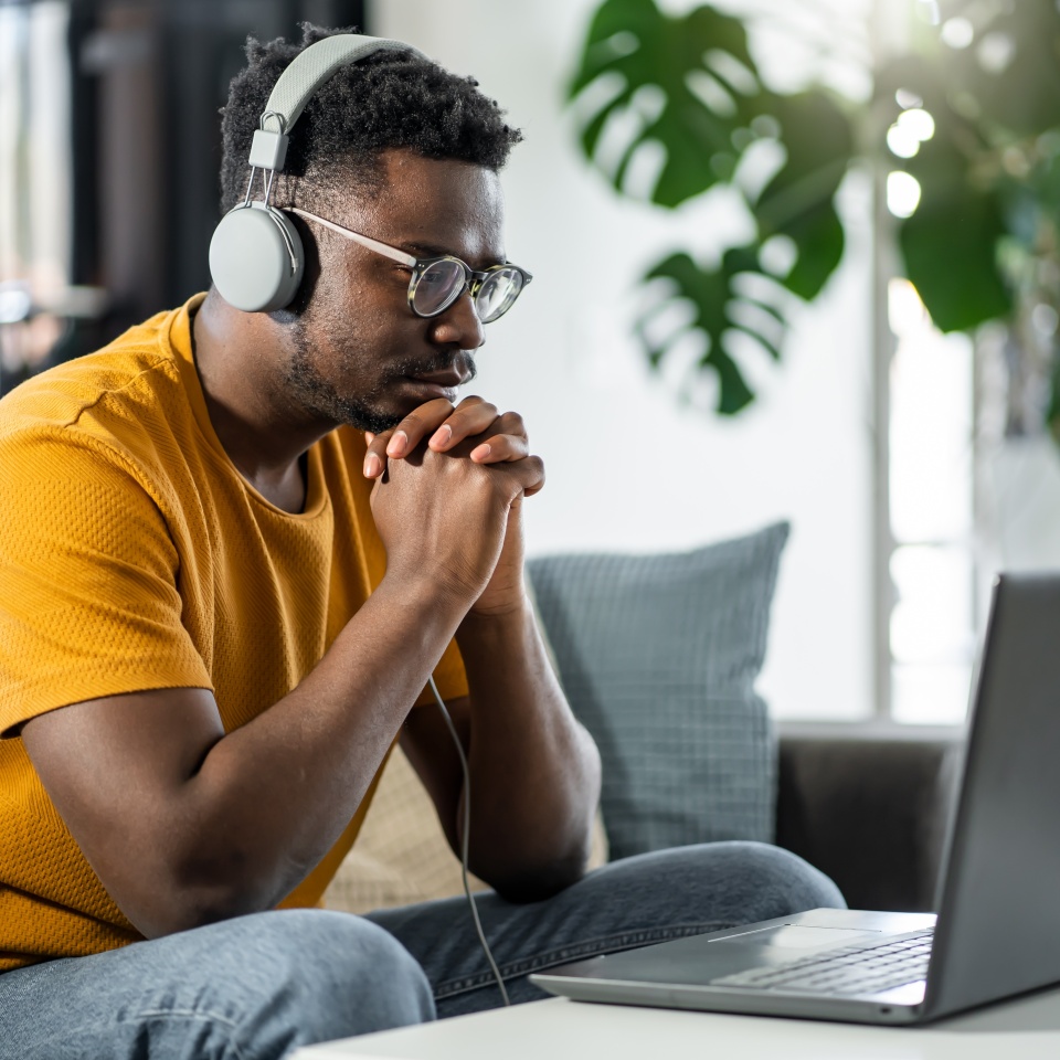 African-American young student at home, listening to online classes, or a webinar over a laptop computer
