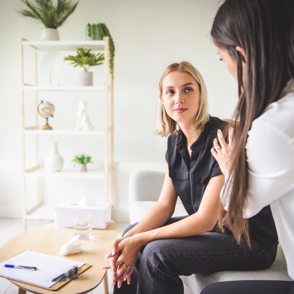 A Psychotherapist supporting depressed teenage girl on couch during appointment in office a Psychotherapy concept