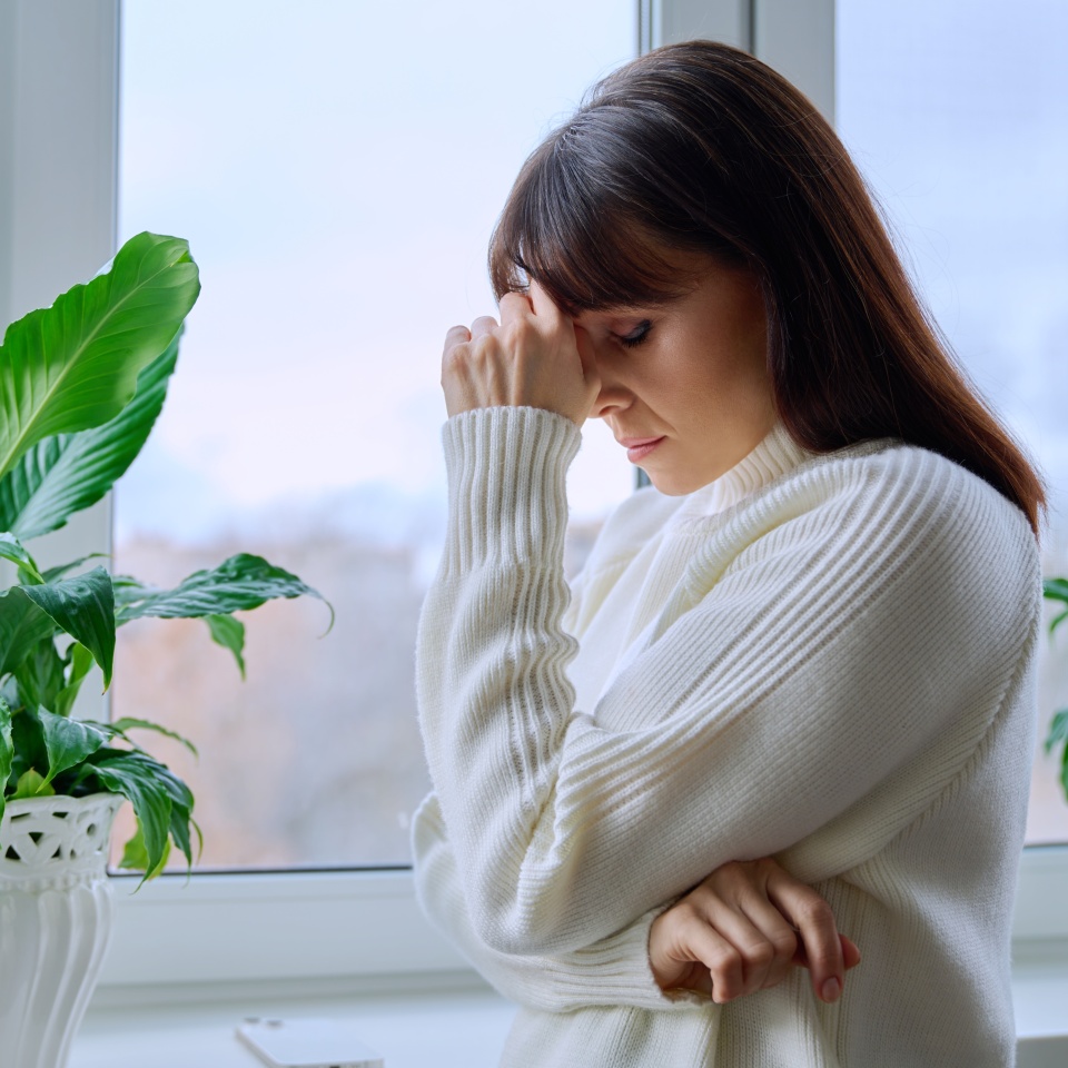 Middle aged woman experiencing stress depression mental pain, at home near window
