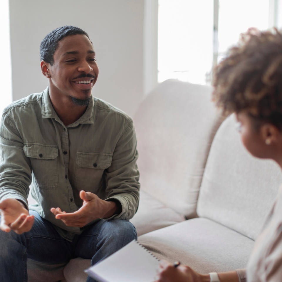 Cheerful positive african american guy having conversation with therapist