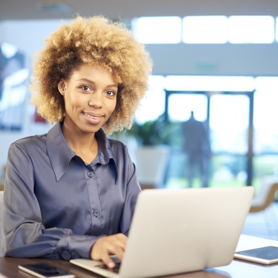A smiling afro-american young businesswoman using her laptop in the office.